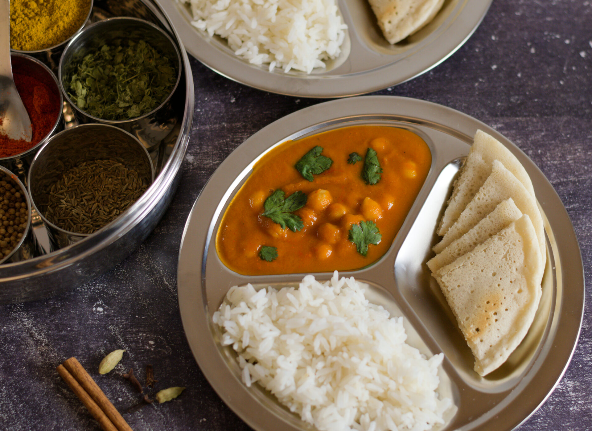 Chana masala on a silver plate with rice and gluten free bread