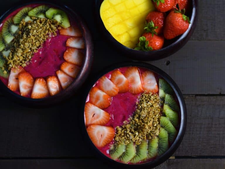 two pitaya dragonfruit smoothie bowls in wooden bowls