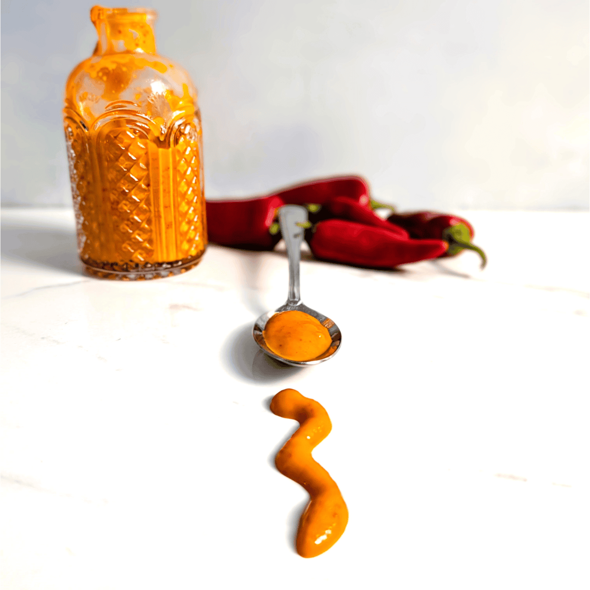 vinegar free hot sauce on a spoon with red hot chili peppers